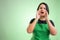 Female cook with green apron and black t-shirt shouting with her hands to her mouth