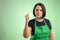 Female cook with green apron and black t-shirt showing fist