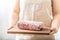 Female cook holding wooden board of raw and frozen beef  meat