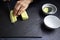 Female cook preparing some pieces of cucumber strips to make sushi on a blackboard