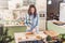 Female cook working in gloves making Japanese sushi rolls slicing them on bamboo mat standing in kitchen