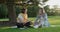 Female counsellor talking with young woman student teenager sitting on lawn in park on grass