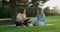 Female counsellor talking with young woman student teenager sitting on lawn in park on grass
