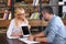 female counselor pointing on digital tablet with blank screen by pen to male patient at table