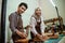 female craftsman with male craftsman smiling while measuring leather material