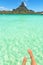 Female crossed legs over tropical blue lagoon and Otemanu mount, Bora Bora, near Tahiti, in French Polynesia.