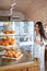 Female customer admires coffee shop croissants selection.