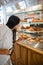 Female customer admires coffee shop croissants selection.