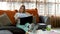 Female cute worker looks paper documents, sits on couch or sofa with laptop PC