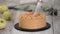 Female cutting a caramel cake with almond, on wooden table.