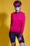 Female Cycling Ideas. Portrait of Positive Female Road Cyclist in Professional Long Sleeve Jersey Outfit Posing Against Yellow