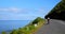 Female cyclist cycling on a coastal road on a sunny day 4k