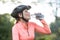 Female cyclist drinking water in forest