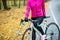 Female Cyclist in Pink Jacket Resting with Road Bicycle in the Cold Sunny Autumn Day