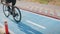 Female cyclist riding bicycle on bike lane in park. Close up of woman muscular fit legs in cycling shoes pushing pedals on bicycle