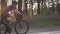 Female cyclist riding road bicycle in the park with the sun shining through trees. Cinematic cycling concept. Slow motion