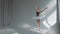 Female dancer does ballet exercises in stage dress with open back. Rehearses dance moves in the spacious and brightly