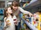 Female with daughter choosing canned goods in food store