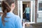 Female Delivery Driver Leaving Package Outside House For Safety Observing Social Distancing During Coronavirus Pandemic