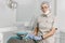 Female dentist in a medical mask and cap standing in a dental clinic among modern dental equipment. Portrait of a female