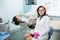 Female dentist with patient in the dental clinic. Doctor wearing glasses, white uniform and pink gloves