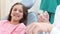 Female dentist showing dental instruments to a little girl