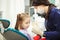 Female dentist shows to little patient artificial human jaw