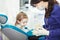 Female dentist shows to little patient artificial human jaw