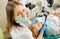 Female dentist treating caries using microscope at the dentist office