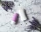 Female deodorant and lavender flowers on marble background, flat lay