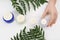 Female dermatologist with jars of skin care products on white background