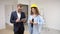 Female designer and happy male owner in suit at new apartments. Girl in yellow helmet holding measuring meter. Repair home