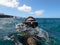 A female diver takes a funny selfie while diving into the water with half her head submerged