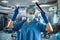 Female doctor in blue uniform and protective mask, gloves writes notes on the clipboard in operating room