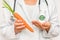 Female doctor compare pile of pills with fresh carrot