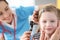 Female doctor conducts medical examination of ear with an otoscope to little girl