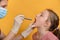 A female doctor examines a girl`s oral cavity with a diagnostic medical flashlight