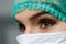 Female doctor face wearing protective mask and green surgeon cap