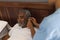 Female doctor fitting a senior man with hearing aid in bedroom