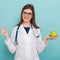 Female doctor in glasses with apple and pills