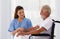 Female doctor helping care holding hands to encourage talk Caucasian older man, older adult, patient in a wheelchair