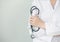 Female doctor holding stethoscope in hand standing in white background copy-space. hospital and professional concept