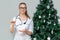 A female doctor holds pills in background of a Christmas tree. Treatment of digestion from overeating during holidays