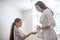 Female doctor in a lab coat spraying sanitizer to girls hands