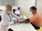 Female doctor in medical facemask measure blood pressure with electronic monitor in hospital.