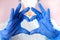 Female doctor or nurse in medical mask and hands in protective gloves shows the symbol of the heart. Love, care and safety.