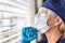 Female Doctor or Nurse Praying At Window Wearing Medical Face Mask and Goggles