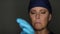 Female Doctor or Nurse Wearing Surgical Cap and Scrubs Putting on Gloves