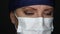 Female Doctor or Nurse Wearing Surgical Mask and Cap Looking Around and Into The Camera