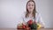 A female doctor or nutritionist sitting at the table and holding with different fruits and vegetables. Healthcare